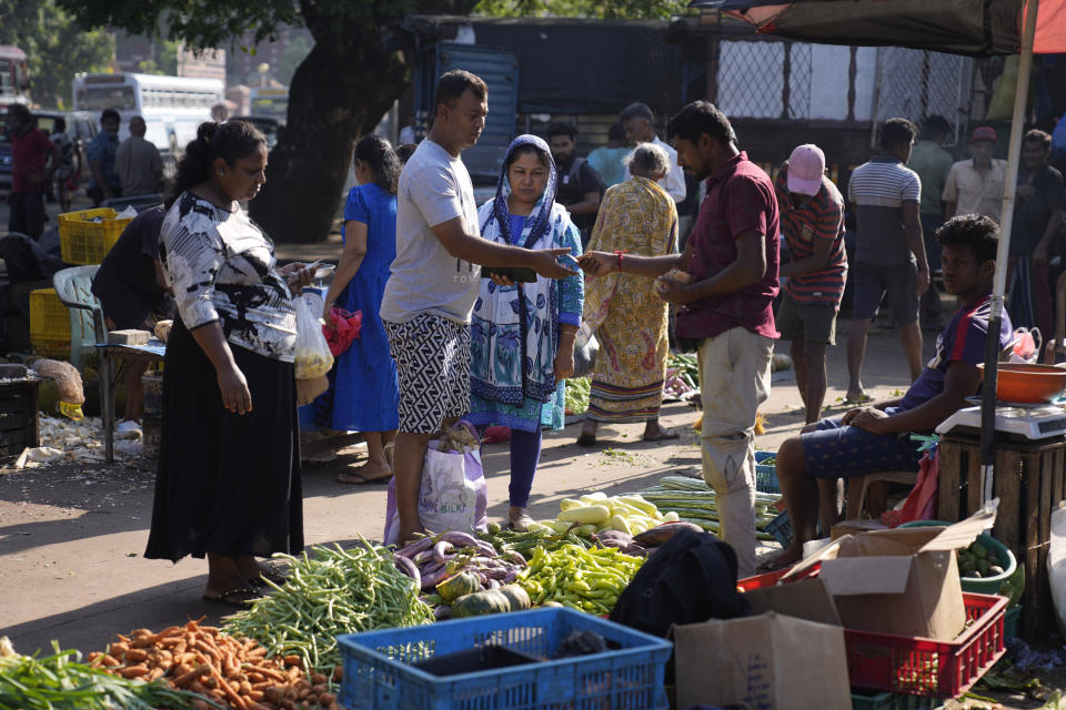 People buy vegetables at a market in Colombo, Sri Lanka, Wednesday, Dec. 13, 2023. The International Monetary Fund executive board has approved the release of $ 337 million second tranche of a bailout package to help Sri Lanka recover from its worst economic crisis. (AP Photo/Eranga Jayawardena)