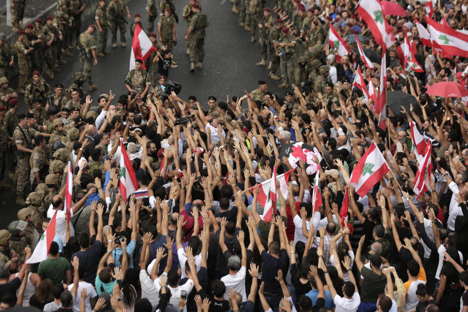 Anti-government protesters shout slogans against the Lebanese government during a protest in the town of Jal el-Dib north of Beirut, Lebanon, Wednesday, Oct. 23, 2019. Lebanese troops have opened several major roads around the country scuffling with anti-government protesters who have paralyzed Lebanon for the seventh day. (AP Photo/Hassan Ammar)