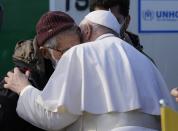 Pope Francis hugs a migrant during his visit at the Karatepe refugee camp, on the northeastern Aegean island of Lesbos, Greece, Sunday, Dec. 5, 2021. Pope Francis is offering comfort migrants at a refugee camp on the Greek island of Lesbos. He is blasting what he says is the indifference and self-interest shown by Europe "that condemns to death those on the fringes." (AP Photo/Alessandra Tarantino)