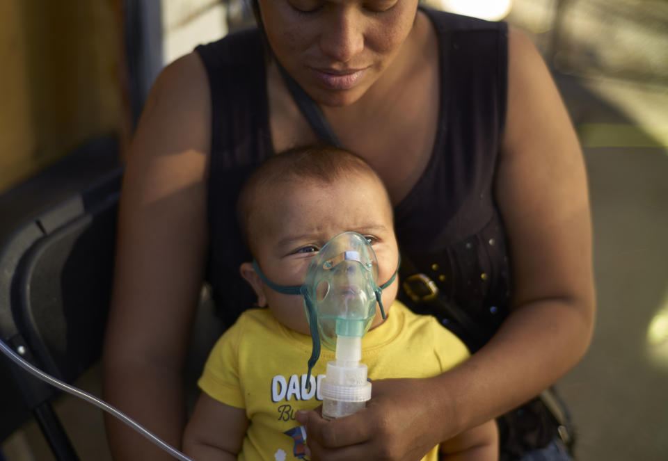 Honduran migrant Janet Zuniga holds her five-month-old son Linder, as he receives medical treatment outside a shelter, Monday, Nov. 26, 2018, in Tijuana, Mexico. A day after a march by members of the migrant caravan turned into an attempt to breach the U.S. border with Mexico, many migrants appeared sullen, wondering whether the unrest had spoiled whatever possibilities they might have had for making asylum cases. (AP Photo/Gregory Bull)