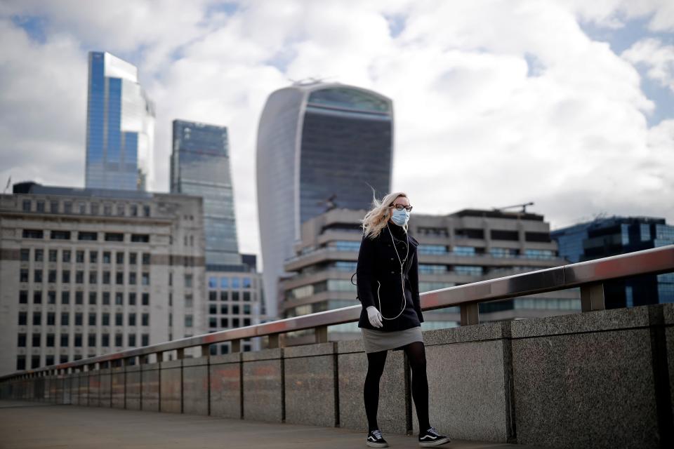 A woman wearing PPE (personal protective equipment), including a face mask as a precautionary measure against COVID-19, walks across London Bridge away from the City of London, in central London on May 13, 2020, as people start to return to work after COVID-19 lockdown restrictions were eased. - Britain's economy shrank two percent in the first three months of the year, rocked by the fallout from the coronavirus pandemic, official data showed Wednesday, with analysts predicting even worse to come. Prime Minister Boris Johnson began this week to relax some of lockdown measures in order to help the economy, despite the rising death toll, but he has also stressed that great caution is needed. (Photo by Tolga Akmen / AFP) (Photo by TOLGA AKMEN/AFP via Getty Images)