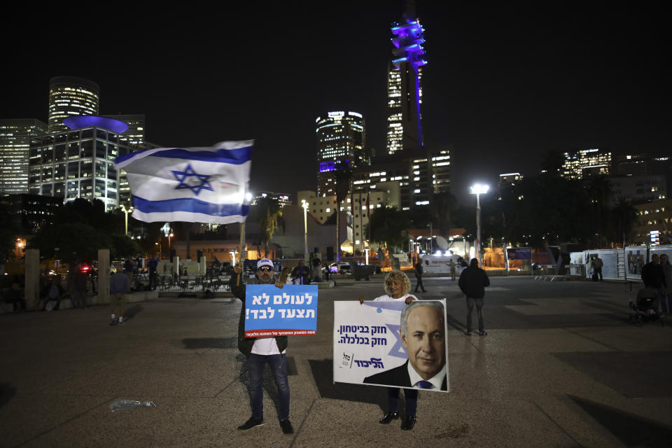 Israeli Prime Minister supporters stand during a support rally in Tel Aviv, Israel, Tuesday, Nov. 26, 2019. The sign with Hebrew reads: " You never walk alone." (AP Photo/Oded Balilty)