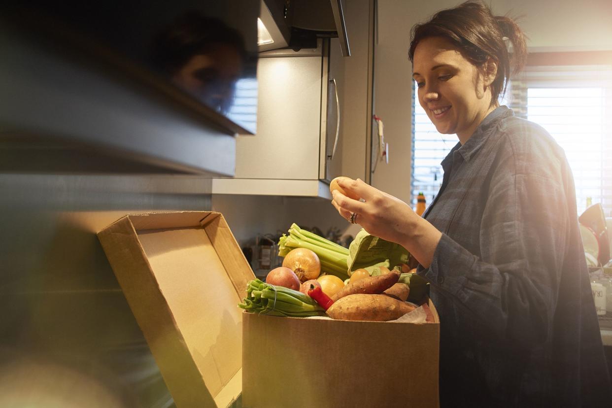 woman in kitchen going through her grocery delivery box