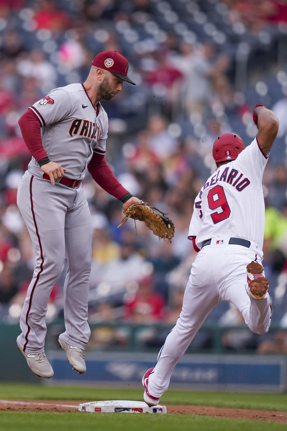 Arizona Diamondbacks first baseman Christian Walker (53) can't make the tag on Washington Nationals' Jeimer Candelario (9), who was safe at first base, during the first inning of a baseball game at Nationals Park, Wednesday, June 7, 2023, in Washington. (AP Photo/Alex Brandon)
