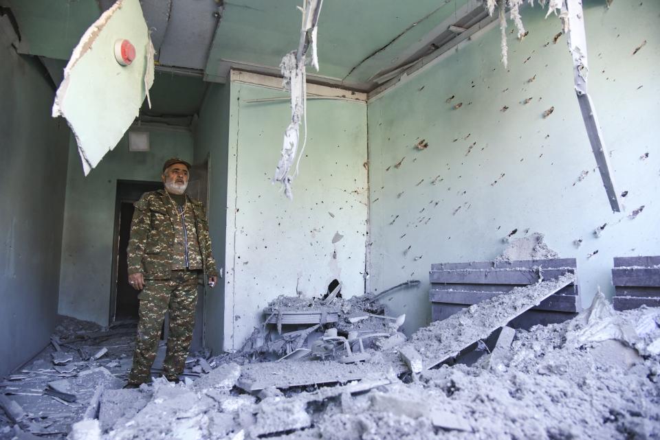 A man wearing a military uniform stands inside a house destroyed by shelling during a military conflict in Stepanakert in the separatist region of Nagorno-Karabakh, Saturday, Oct. 17, 2020. Stepanakert, the regional capital of Nagorno-Karabakh, came under intense shelling overnight, leaving three civilians wounded, according to separatist authorities. (David Ghahramanyan, NKR InfoCenter/PAN Photo via AP)