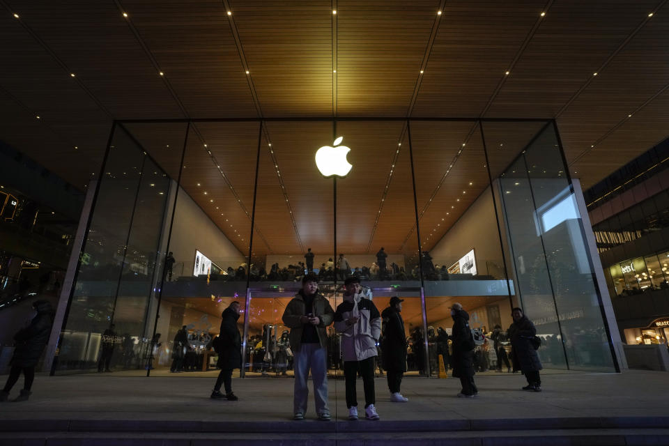 Shopper stand watch as people visit an Apple Store at an outdoor shopping mall in Beijing on Saturday, Dec. 23, 2023. It was tumultuous 2023 for the Chinese economy. Some of the world's biggest brands said they were weighing, or already have decided, to shift manufacturing away from China amid unease about security controls, government protection of their Chinese rivals and Beijing's wobbly relations with Washington. But there was at least one bright spot for Beijing amid all the tough news about declining foreign investment: American fast food companies have announced a surge of investment in a market of 1.4 billion people. KFC, McDonald's and Starbucks are among companies in recent months that have announced plans for major investment in China. (AP Photo/Andy Wong)