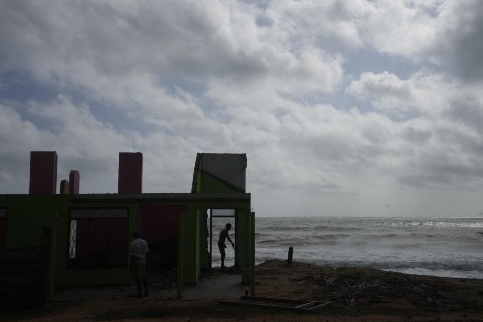 Dilrukshan Kumara salvages a doorway from their home destroyed by erosion along the coast in Iranawila, Sri Lanka, Thursday, June 15, 2023. Much like the hundreds of other fishing hamlets that dot the coastline, the village of Iranawila suffers from coastal erosion. (AP Photo/Eranga Jayawardena)