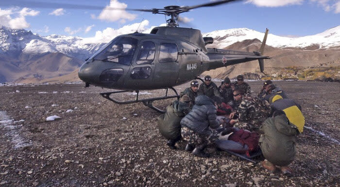 Military in front of a helicopter at Everest BC with a bundle 