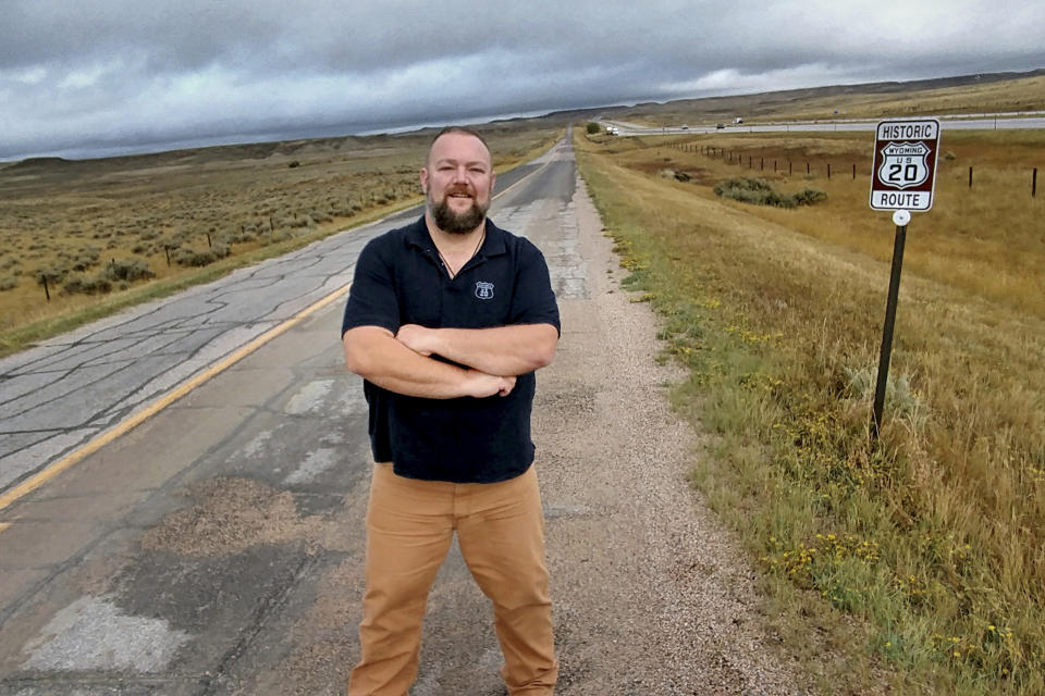 In this Sept. 25, 2017, photo, Bryan Farr, president of the Historic Route 20 Association in Chester, Mass, stands on an original alignment of U.S. Route 20 near Orin, Wy. Highway 20 was moved to the neighboring Interstate 25 where speed limits are set at 80 mph. “Almost every town has a story to tell,” Farr, said. (Bryan Farr via AP)