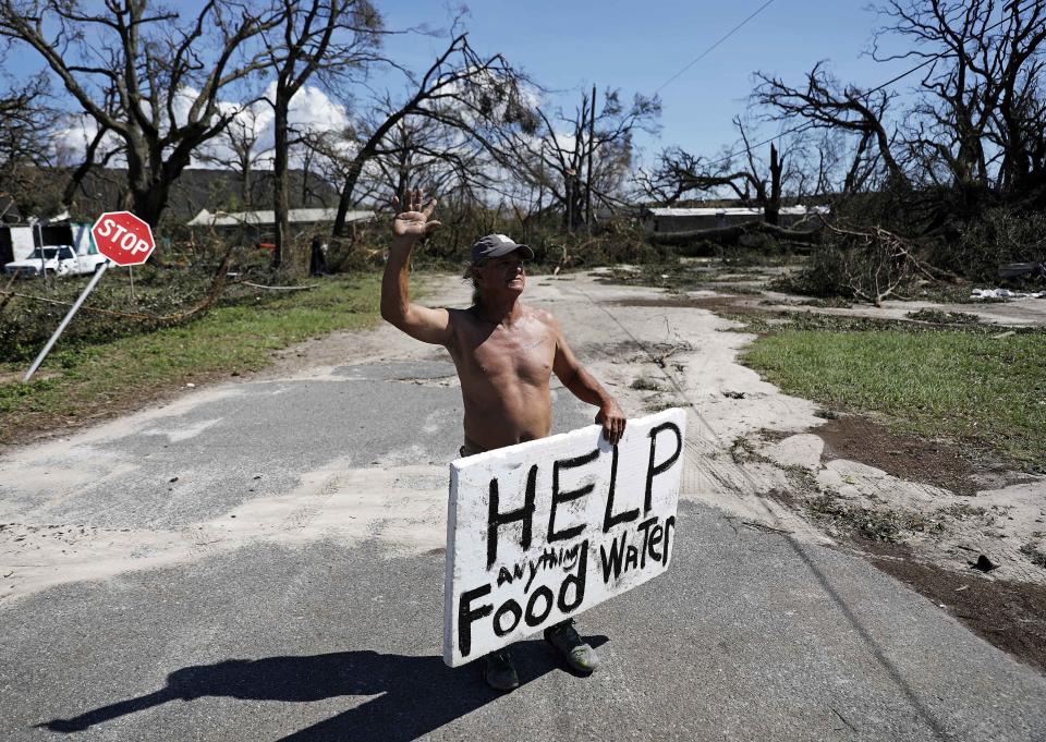 Michael Williams, 70, waves to passing motorists while looking for food and water as downed trees prevent him from driving out of his damaged home with his family in the aftermath of Hurricane Michael in Springfield, Fla., Thursday, Oct. 11, 2018. "I don't know what I'm going to," said Williams. (AP Photo/David Goldman)
