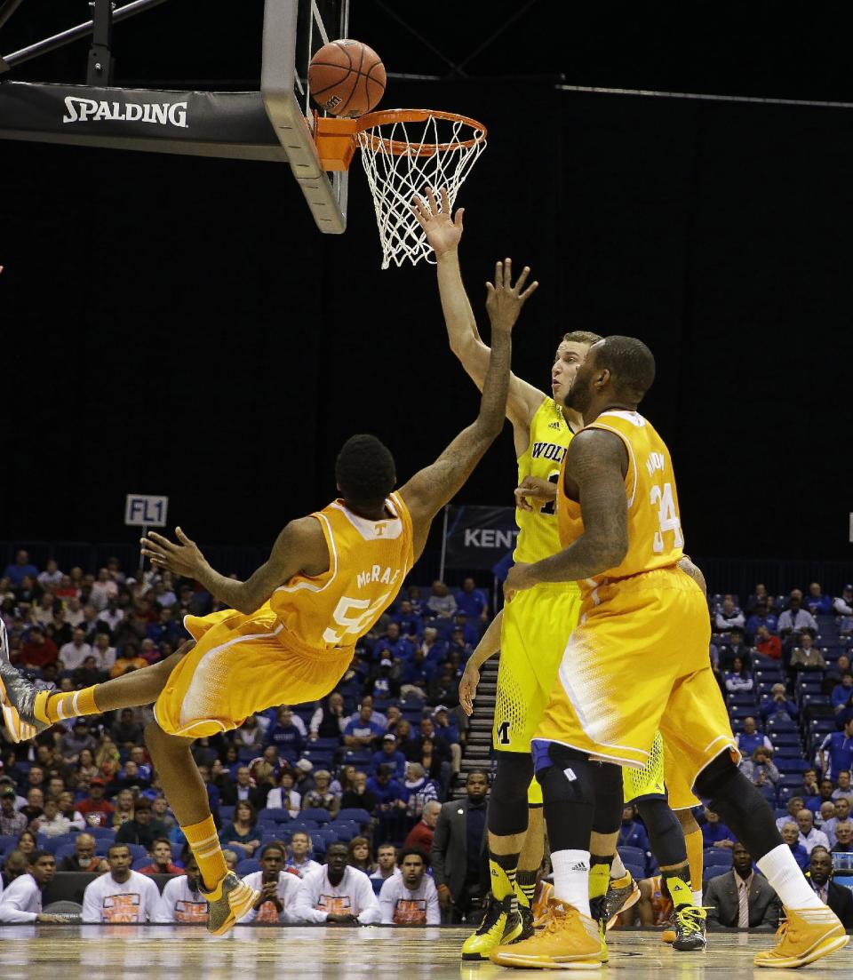 Tennessee's Jordan McRae, left, shoots against Michigan guard Nik Stauskas as Tennessee's Jeronne Maymon, right, watches during the second half of an NCAA Midwest Regional semifinal college basketball tournament game against the Michigan Friday, March 28, 2014, in Indianapolis. (AP Photo/David J. Phillip)