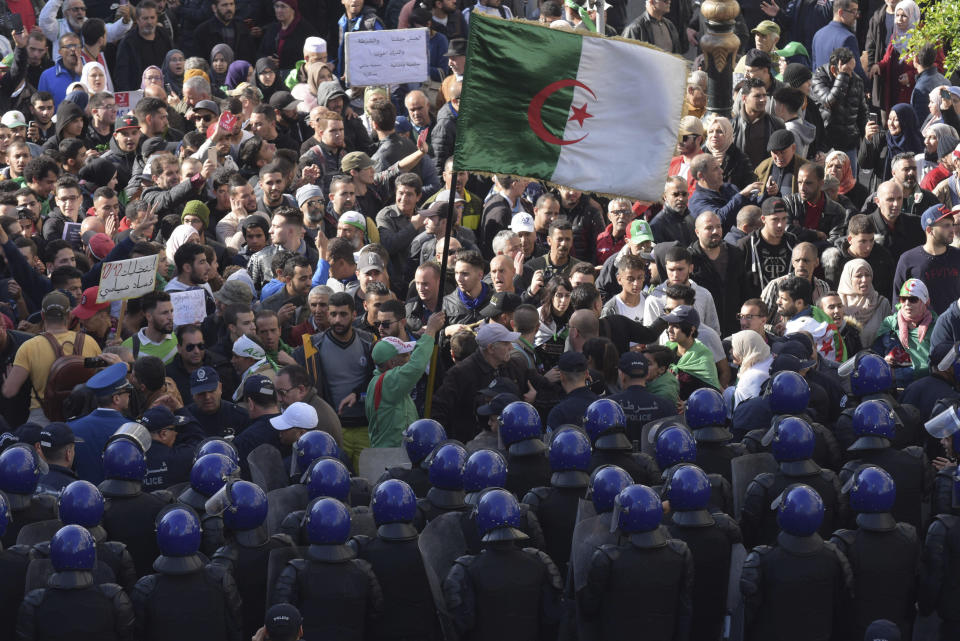 Security forces stand guard as Algerian demonstrators take to the streets in the capital Algiers to protest against the government and reject the upcoming presidential elections, in Algeria, Wednesday, Dec. 11, 2019. Algeria's powerful army chief promises that a presidential election on Thursday will define the contours of a new era for a nation where the highest office has stood vacant for eight months. The tenacious pro-democracy movement which forced leader Abdelaziz Bouteflika to resign after 20 years in power doesn't trust the confident claim and is boycotting the vote. (AP Photo/Toufik Doudou)