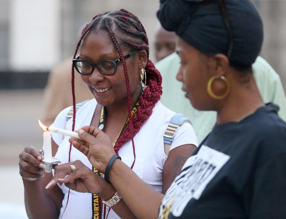 Marquetta Williams, left, helps Jolanda Jackson, right, light her candle as they all remembered the life of James R. Williams, Marquetta's late husband, in Canton on Saturday, July 16, 2022. Williams was shot and killed by Canton Police on New Year's Eve.