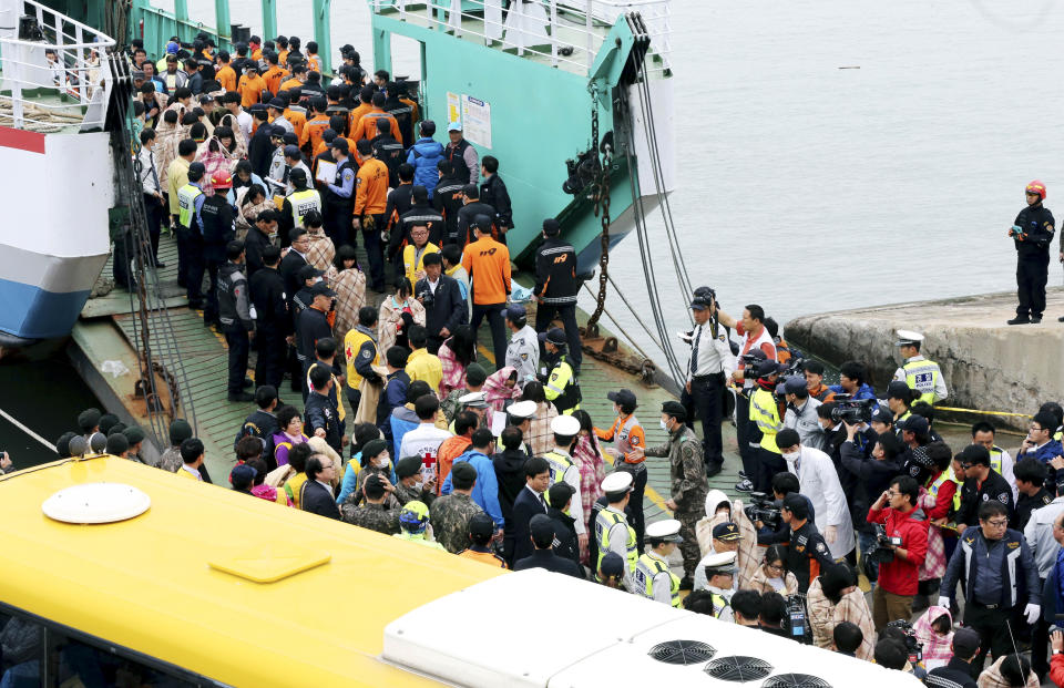 Rescued passengers are escorted by members of a rescue team upon their arrival at a port in Jindo, south of Seoul, South Korea, Wednesday, April 16, 2014. More than 100 people were still unaccounted Wednesday several hours after a ferry carrying 476, most of them high school students, sank in cold waters off South Korea's southern coast, killing at least two and injuring 14, officials said. (AP Photo/Yonhap, Park Chul-heung) KOREA OUT