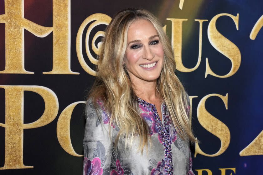 A woman with long blond hair smiling in a patterned dress