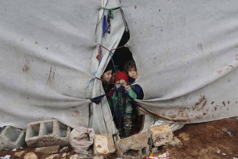 Niños desplazados miran desde una carpa en Azaz, Siria