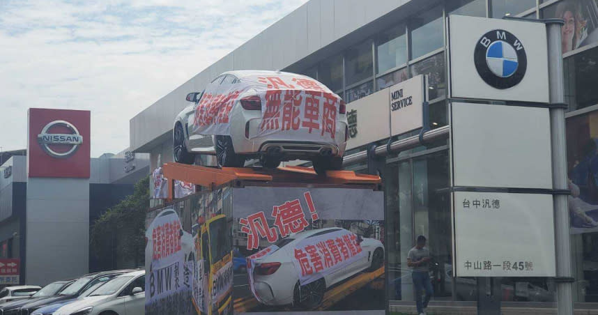 羅男因與台中汎德汽車間的購車糾紛，前天早上把發生問題的車輛放在自己安排的貨櫃上方，而且就放在車商展示中心門前。（圖／讀者提供）