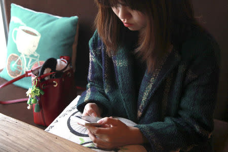 A woman uses an app on a mobile phone at a cafe in Beijing, China, April 11, 2016. REUTERS/Shirley Feng/File Photo