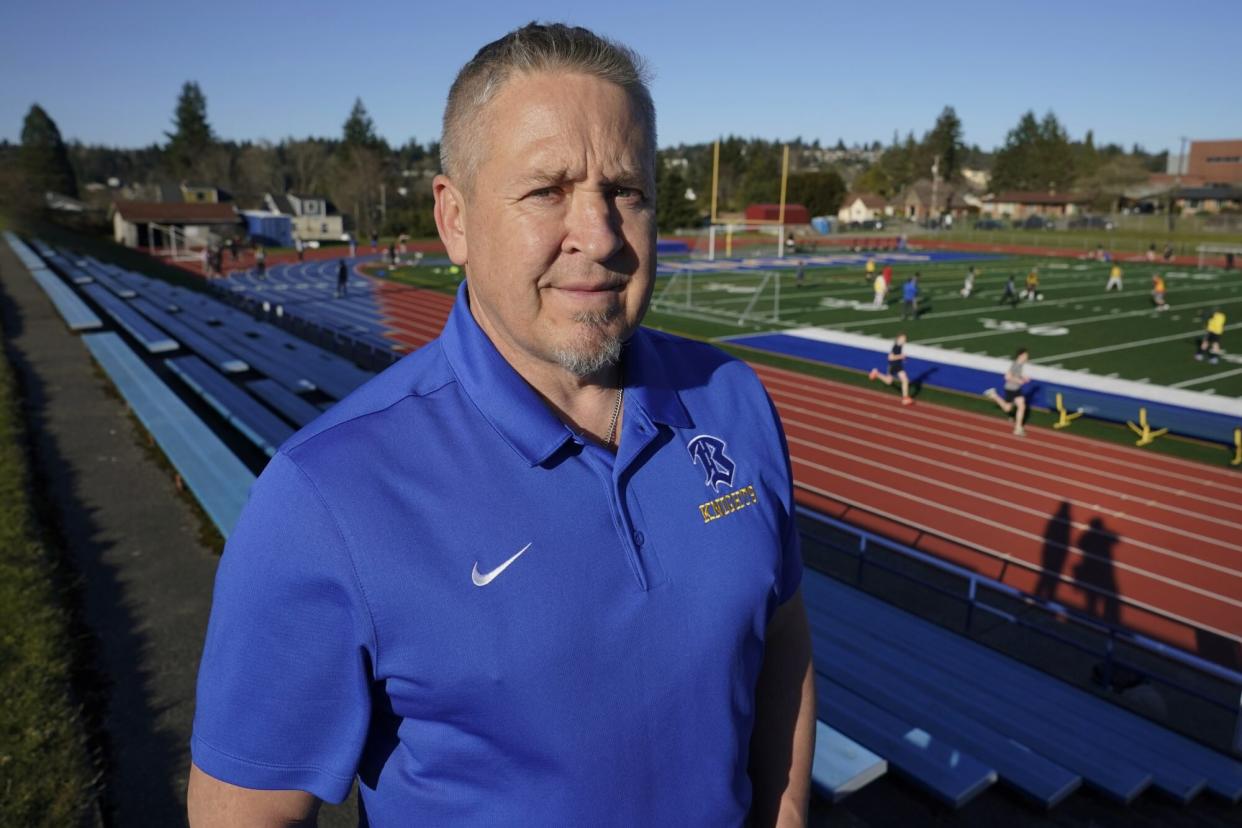 Joe Kennedy, a former assistant football coach at Bremerton High School in Bremerton, Wash., poses for a photo March 9, 2022, at the school's football field. After losing his coaching job for refusing to stop kneeling in prayer with players and spectators on the field immediately after football games, Kennedy will take his arguments before the U.S. Supreme Court on Monday, April 25, 2022, saying the Bremerton School District violated his First Amendment rights by refusing to let him continue praying at midfield after games. (AP Photo/Ted S. Warren)