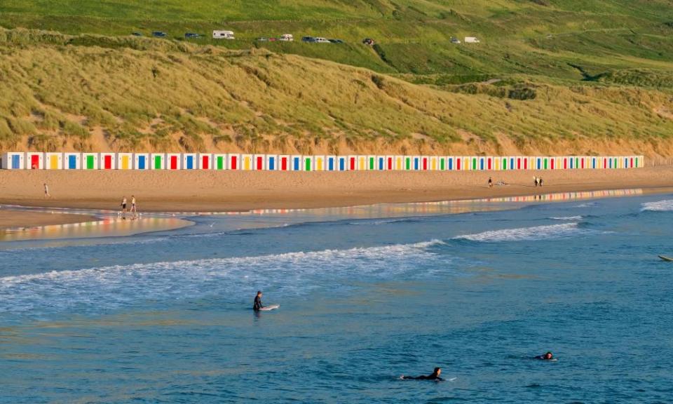 Saunton Sands beach with sand dunes and a line of colourful, painted beach huts on the beach in Devon