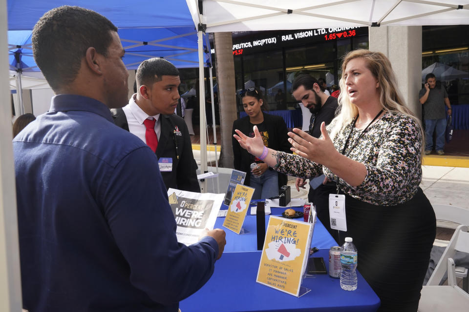 Brittany Dotson explains job opportunities at 0 Percent to job seekers at the Venture Miami Tech Hiring Fair Thursday, April 14, 2022, in Miami. America’s employers added 428,000 jobs in April, extending a streak of solid hiring that has defied punishing inflation, chronic supply shortages, the Russian war against Ukraine and much higher borrowing costs. (AP Photo/Marta Lavandier)