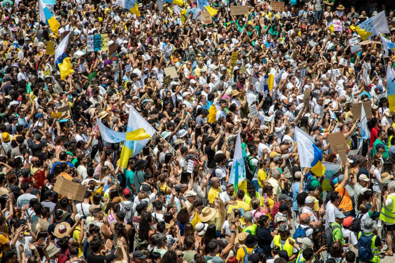 People hold flags during a demonstration against the tourism model under the slogan 'Canarias has a limit'. Europa Press Canarias/EUROPA PRESS/dpa