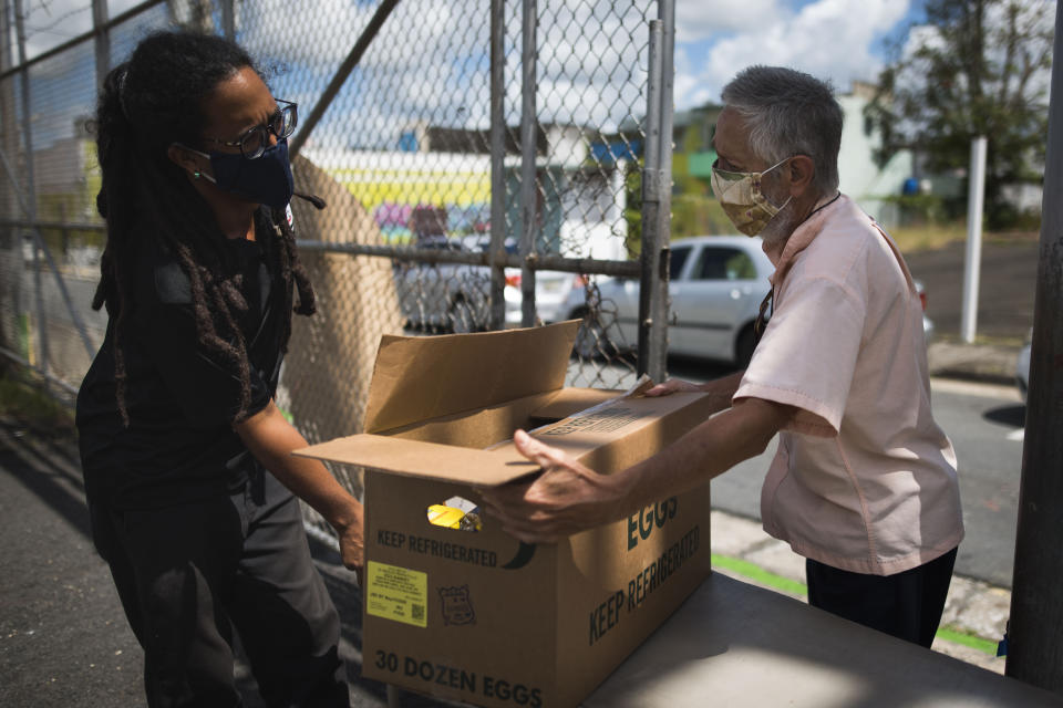 Manuel Berrios, right, takes a food donation from Giovanni Roberto, coordinator of Comedores Sociales (Social Canteens) a non-profit entity dedicated to offering hot meals in the middle of the Covid-19 pandemic, in Caguas, Puerto Rico, Wednesday, April 29, 2020. Puerto Rico's government is refusing to open school cafeterias amid a coronavirus pandemic as a growing number of unemployed parents struggle to feed their children. (AP Photo/Carlos Giusti)
