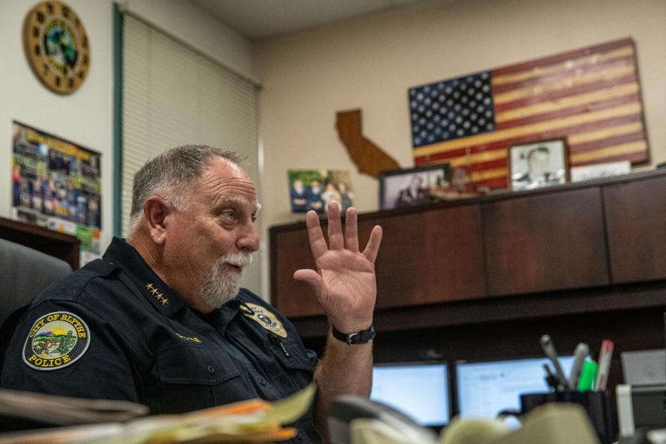 Blythe's police chief sits in his office with an American flag on the wall.