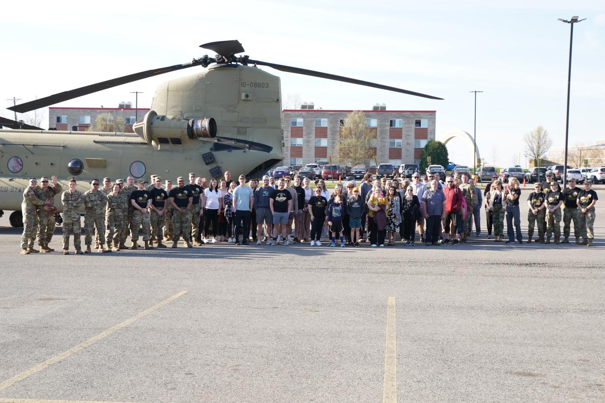 Participants in Meet the Army Community Day at Adrian College pose for a photo Friday, April 14, 2023, with the CH-47 Chinook helicopter that flew in for the event.