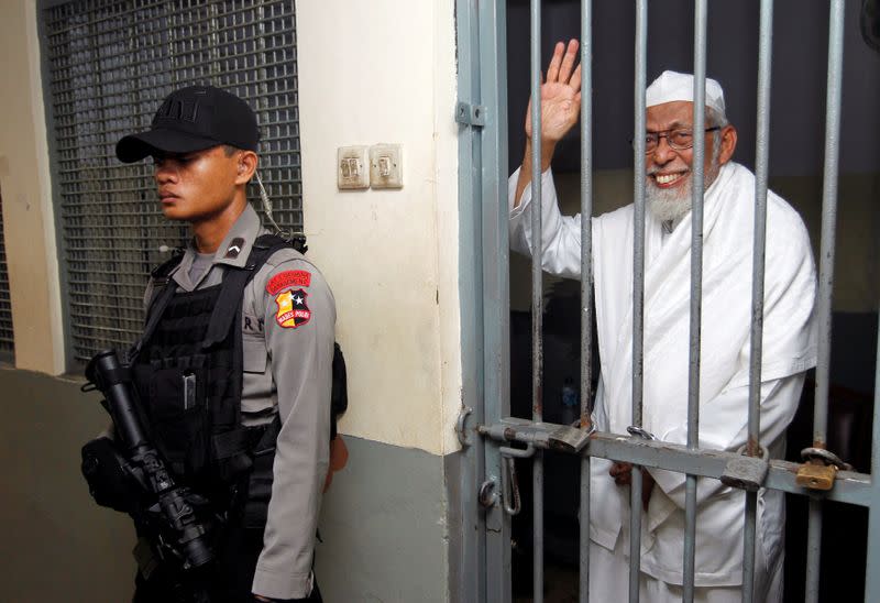 FILE PHOTO: Islamic cleric Abu Bakar Bashir waving as he waits inside a cell before trial at the South Jakarta court