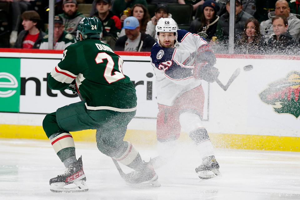 Columbus Blue Jackets right wing Oliver Bjorkstrand (28) shoots in front of Minnesota Wild defenseman Matt Dumba (24) in the second period of an NHL hockey game Saturday, March 26, 2022, in St. Paul, Minn. (AP Photo/Andy Clayton-King)