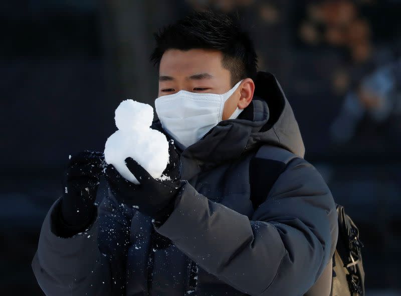 A man wearing protective mask makes a snowman at Sapporo Odori Park in Sapporo, Hokkaido