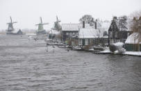 Snow and strong winds pounded houses and windmills along the Zaanse Schans river in Zaandam, Netherlands, Sunday, Feb. 7, 2021. (AP Photo/Peter Dejong)