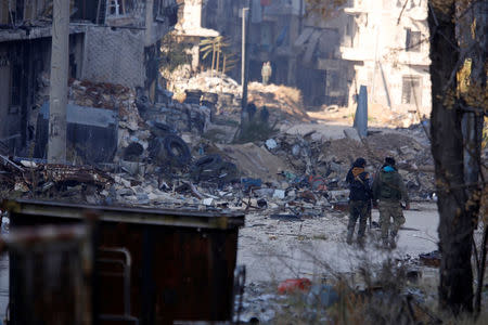 Forces loyal to Syria's President Bashar al-Assad walk past damaged buildings in a government held area of Aleppo, Syria December 9, 2016. REUTERS/Omar Sanadiki