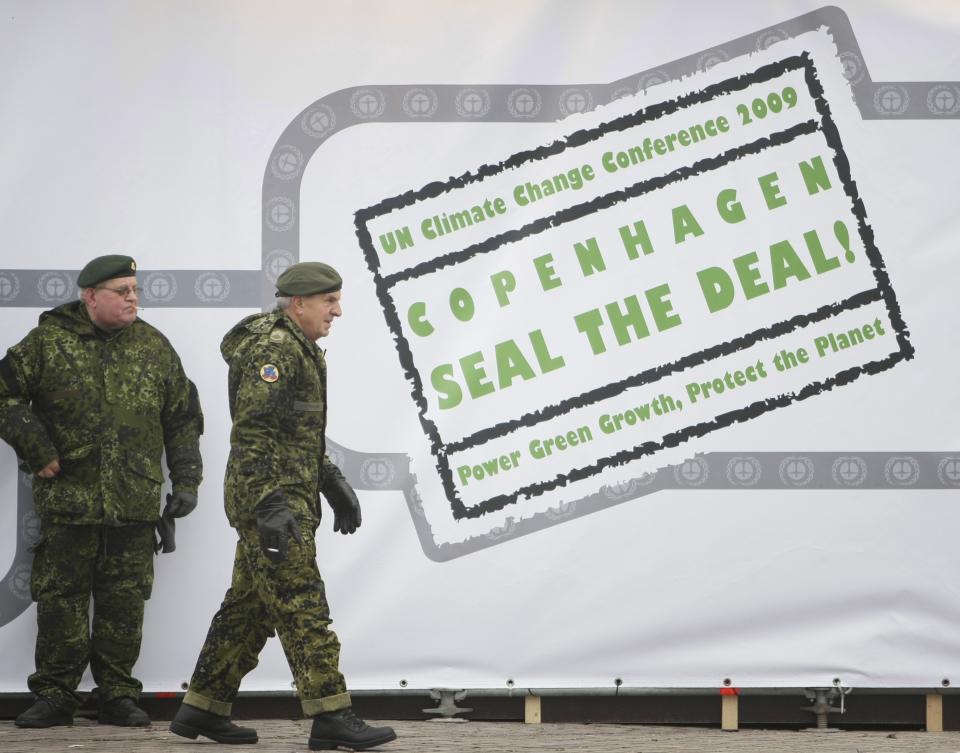 FILE - Danish military appear next to a sign reading "Copenhagen Seal the Deal" in the center of Copenhagen, Dec. 12, 2009. (AP Photo/Peter Dejong, File)