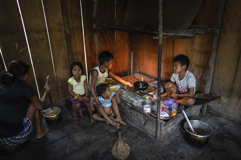 Members of the Padilla family prepare fried bananas for breakfast in Sucusari, Peru, Thursday, May 30, 2024. In the community of thatched houses, the routine of the some 180 inhabitants is mostly traditional. They fish, hunt and grow fruit for local markets, mostly aguaje, an Amazon delicacy. (AP Photo/Rodrigo Abd)