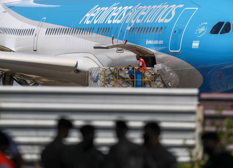 Un trabajador descarga neveras portátiles con dosis de la vacuna contra el COVID-19 Sputnik V, en el Aeropuerto Internacional de Ezeiza, en Buenos Aires, Argentina