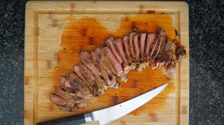 Slices of steak on board with knife