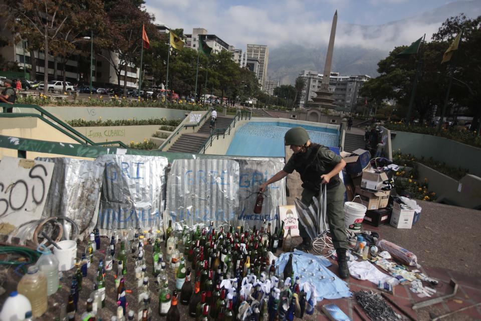 A Bolivarian National Guard places a glass bottles with others items allegedly seized from demonstrators after a raid in Plaza Altamira, Caracas, Venezuela, Monday, March 17, 2014. The Bolivarian National Guard conducted raids in the Chacao district this Monday morning vacating the barricades installed there in order to prevent anti-government protests from happening in the area. (AP Photo/Esteban Felix)