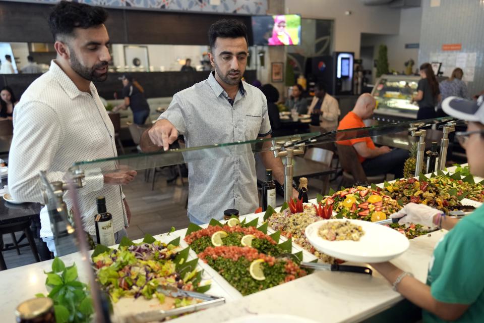 Abdul Wasi Safi, right, and his brother Samiullah pick out food for lunch, Wednesday, April 26, 2023, in Houston. Abdul recently arrived in Houston after being released from a Texas immigration detention center, but has no documentation to allow him to begin a normal life with his brother while he applies for asylum. (AP Photo/David J. Phillip)