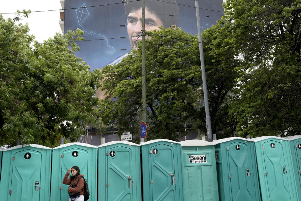 A woman waits her turn to use a toilet in front of a mural of Diego Maradona by artist Martin Ron in Buenos Aires, Argentina, Sunday, Oct. 30, 2022. Sunday marks the birth date of Maradona who died on Nov. 25, 2020 at the age of 60.(AP Photo/Rodrigo Abd)