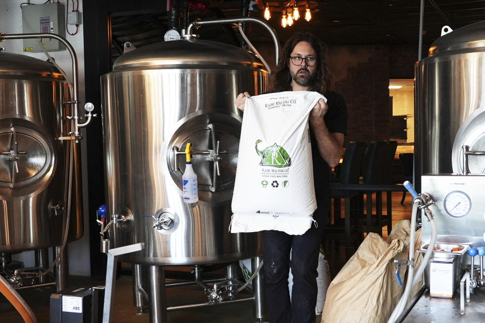 Mitchell Dougherty, the brewmaster at Side Hustle Brews and Spirts, carries a sack at their brew pub in Abu Dhabi, United Arab Emirates, Monday, May 13, 2024. Abu Dhabi has overhauled its laws to allow for the micro and craft breweries that have taken the rest of the world by storm, part of a wider reconsideration of alcohol policies in this Islamic nation increasingly drawing tourists. (AP Photo/Malak Harb)