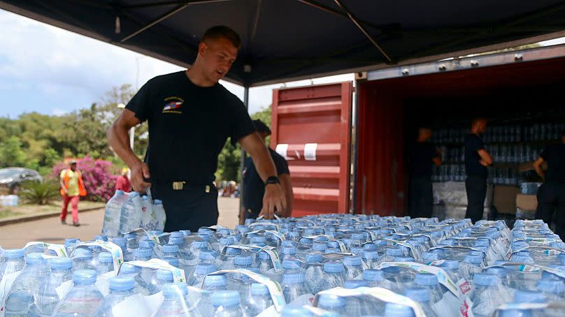 A security officer picks up water bottles for residents in Tsoundzou, on the French Indian Ocean territory of Mayotte, 21 October2023.