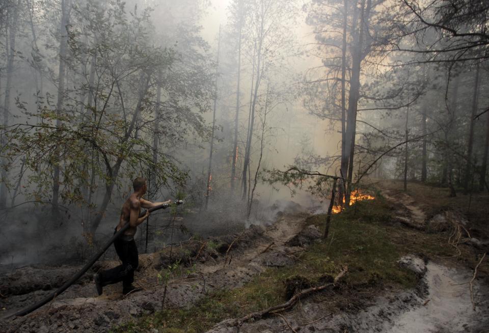 FILE - In this Aug. 7, 2010 file photo, a firefighter tries to stop a forest fire near the village of Verkhnyaya Vereya in Nizhny Novgorod region, some 410 km (255 miles) east of Moscow. Twenty-first century disasters such as killer heat waves in Europe, wildfires in the United States, droughts in Australia and deadly flooding in Mozambique, Thailand and Pakistan highlight how vulnerable humanity is to extreme weather, says a massive new report from a Nobel Prize-winning group of scientists released early Monday, March 31, 2014. (AP Photo/Alexander Zemlianichenko Jr., File)