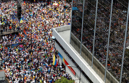 FILE PHOTO: People participating in an opposition rally are reflected in the glass windows of a building. REUTERS/Christian Veron