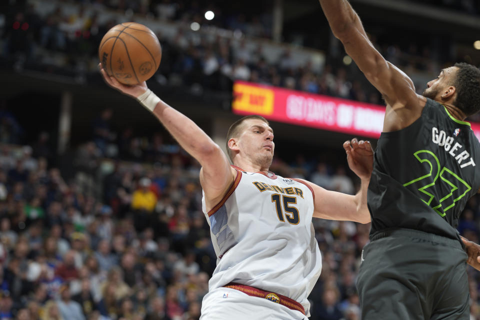Denver Nuggets center Nikola Jokic, left, passes the ball as Minnesota Timberwolves center Rudy Gobert defends during the second half of Game 5 of an NBA basketball first-round playoff series Tuesday, April 25, 2023, in Denver. (AP Photo/David Zalubowski)