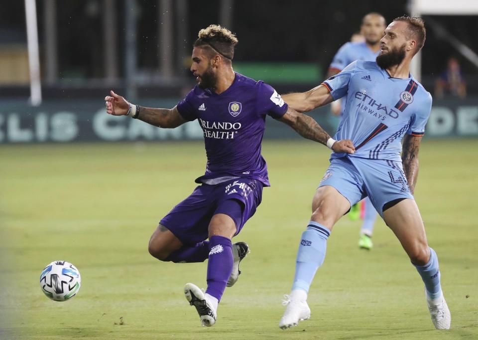 Orlando City's Dom Dwyer (14) pulls the jersey of New York City FC's Maxime Chanot (4) during the MLS is Back tournament soccer match, Tuesday, July 14, 2020, in Lake Buena Vista, Fla. (Stephen M. Dowell/Orlando Sentinel via AP)