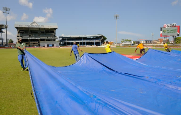 Grounds crew pull a tarp over the field on August 22, 2016 as play is abandoned at Queen's Park Oval in Port of Spain, Trinidad and Tobago