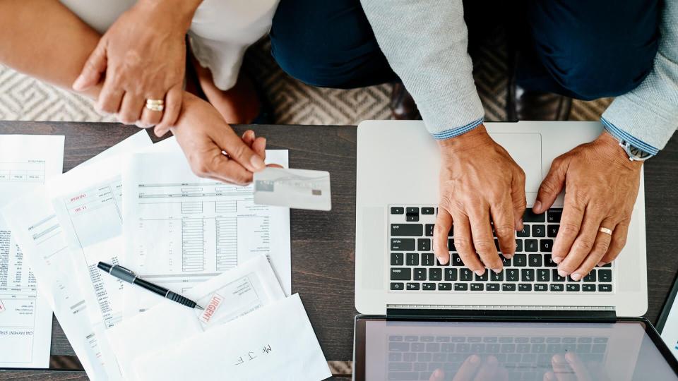 High angle shot of a couple using a laptop and credit card while sorting their finances together at home.