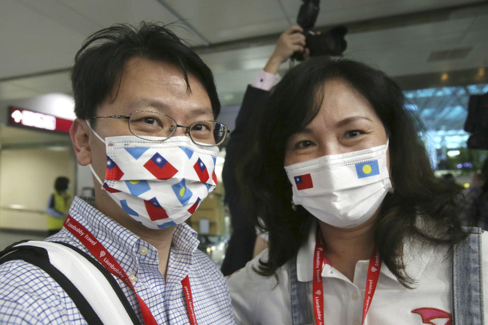 A couple of Taiwanese travelers, the first group of Palau-Taiwan Travel Corridor, wears face masks patterned with national flags of Taiwan and Palau before leaving Taiwan, at Taoyuan International Airport in Taoyuan, northern Taiwan, Thursday, April 1, 2021. The Palau-Taiwan Travel Corridor, allowing people to travel between the islands without a COVID-19 quarantine, has started Thursday. (AP Photo/Chiang Ying-ying)